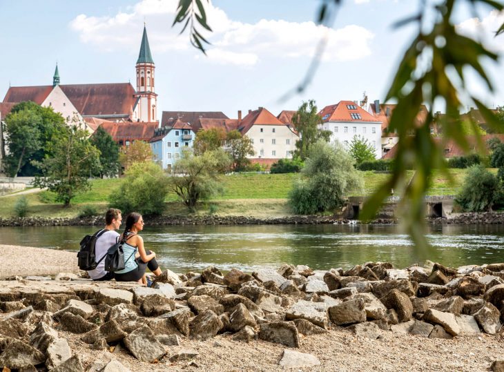 zwei Personen sitzen am Flussrand